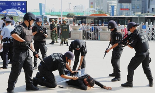 A participant playing the role of knife-wielding attacker in a simulation exercise is controlled by police officers at the south railway station of Urumqi, capital of Northwest Chinas Xinjiang Uygur Autonomous Region on September 4, 2014. The anti-terror drill was aimed to boost local police forces ability to handle an emergency. [Photo: China News Service/ Li Guoxian]