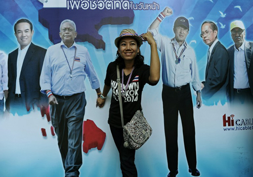 Một người tạo dáng trước tấm panô có hình ảnh của thủ lĩnh biểu tình Suthep Thaugsuban (thứ hai từ trái sang) tại một điểm biểu tình ở Bangkok hôm qua. Ảnh: AFP