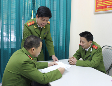 Trung tá Hòa (người đứng) trao đổi kết quả giám định cùng với các đồng đội