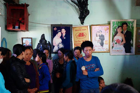 Anh Chương (áo xanh) thất thần trước cái chết của vợ và hai con, tay anh luôn cầm đôi dép của con.