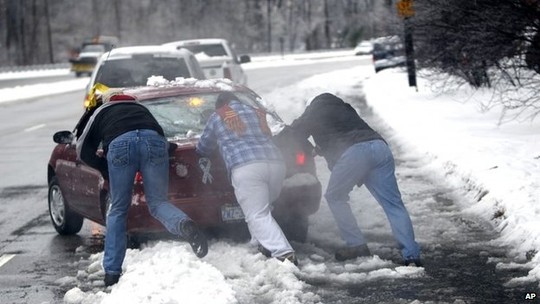 People help push a car from the curb, in Raleigh, North Carolina 13 February 2014