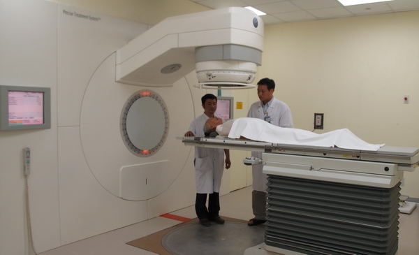 BS. Phạm Nguyên Tường (bên phải) cùng đồng nghiệp chăm sóc người bệnh điều trị 
ung thư bằng máy xạ trị gia tốc tuyến tính ở Trung tâm Ung bướu, BVTW Huế.