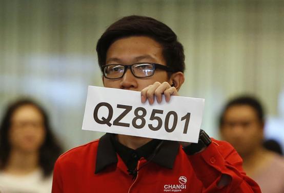 Nhân viên sân bay Changi cầm biển báo nơi tiếp nhận, xử lý thông tin về chiếc máy bay mất tích. Ảnh: Reuters