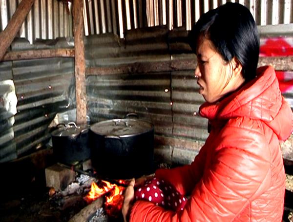 Chị Phan Thị Hoa vợ anh Trương Tuấn Việt ngồi nấu cháo cho chồng và các nạn nhân. Ảnh: Phạm Duy.