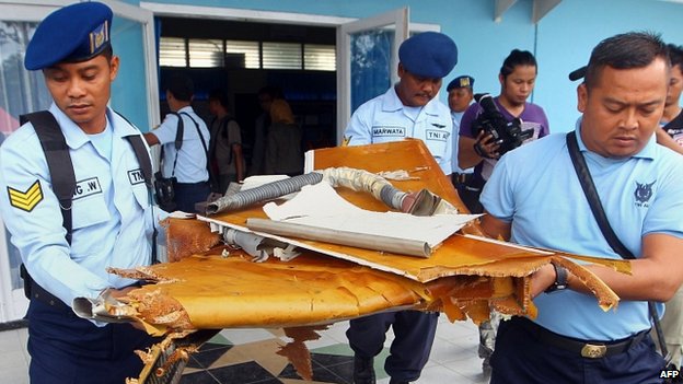 Các quan chức Indonesia khiêng những mảnh vỡ của mảnh bay được trục vớt trên biển.