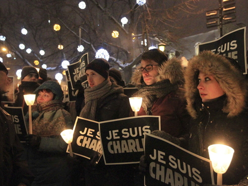 People participate in a vigil to pay tribute to the victims of a shooting, by gunmen at the offices of weekly satirical magazine Charlie Hebdo in Paris, in front of City Hall in downtown Montreal People participate in a vigil to pay tribute to the victims of a shooting, by gunmen at the offices of weekly satirical magazine Charlie Hebdo in Paris, in front of City Hall in downtown Montreal, January 7, 2015. Hooded gunmen stormed the Paris offices of the weekly satirical magazine known for lampooning Islam and other religions, shooting dead at least 12 people, including two police officers, in the worst militant attack on French soil in decades. Placards read I am Charlie. REUTERS/Christinne Muschi (CANADA - Tags: CIVIL UNREST CRIME LAW)