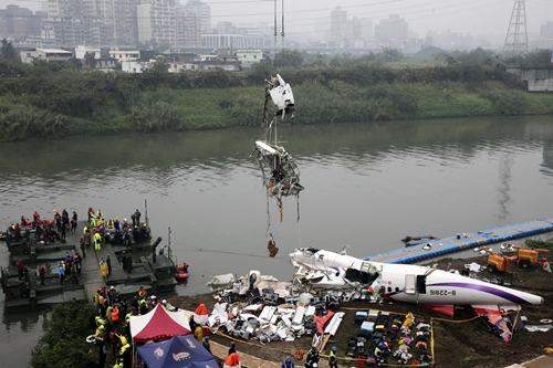 Rescuers lift part of the wreckage of TransAsia Airways plane Flight GE235 after it crash landed into a river, in New Taipei City, February 5, 2015. Taiwanese rescue officials refused to give up hope of finding 12 people still missing on Thursday more than 24 hours after a TransAsia Airways plane crashed into a Taipei river, killing at least 31. REUTERS/Stringer (TAIWAN - Tags: TRANSPORT DISASTER TPX IMAGES OF THE DAY) TAIWAN OUT. NO COMMERCIAL OR EDITORIAL SALES IN TAIWAN. CHINA OUT. NO COMMERCIAL OR EDITORIAL SALES IN CHINA