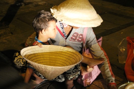 Cảnh người phụ nữ bồng bế trẻ em lao ra đường để xin tiền.