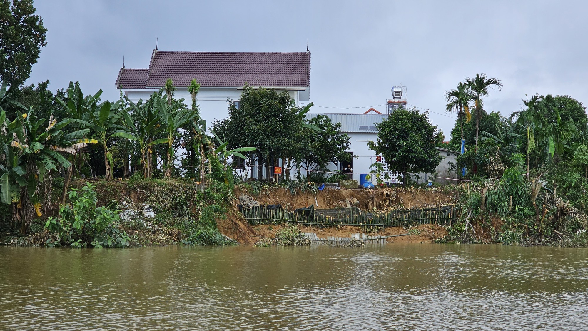 Bờ sông sạt lở nghiêm trọng sau mưa lũ uy hiếp nhà dân ở TP Huế - Ảnh 1.