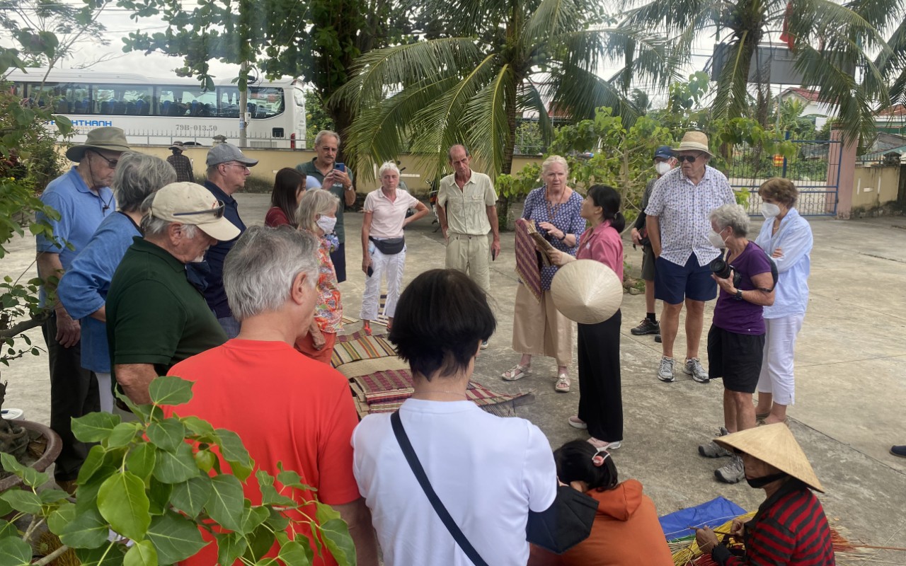 Độc đáo nghề 'làm bằng tay, xoay bằng mông' của người Chăm ở Khánh Hòa- Ảnh 5. Khách Tây thích thú xem nặn gốm, dệt chiếu giữa đồng quê