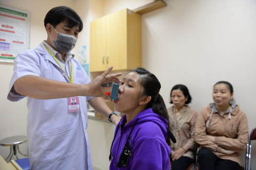 Nhân viên y tế Bệnh viện Đại học Y dược TP.HCM hướng dẫn một bệnh nhân xịt thuốc trị hen. Ảnh: Hữu Khoa