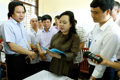 Bộ trưởng Bộ Y tế Nguyễn Thị Kim Tiến kiểm tra sổ ghi nhật ký KCB tại Trạm Y tế xã Minh Châu, huyện Ba Vì, Hà Nội.
