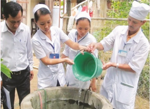 Nhân viên y tế xử lý giếng nước bằng hóa chất khử khuẩn.