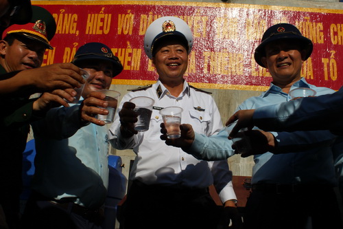 Chuẩn đô đốc Đặng Minh Hải - Phó chính ủy Quân chủng Hải quân (người đứng giữa) và ông Nguyễn Ngọc Tuấn - Phó chủ tịch thường trực HĐND TP. Hà Nội dùng nước ngọt được lọc từ nước biển do máy lọc nước của Hà Nội tặng đảo chìm.