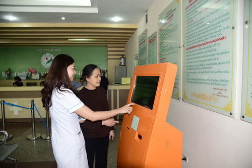Nhân viên y tế hướng dẫn người bệnh tra cứu sổ y bạ điện tử.