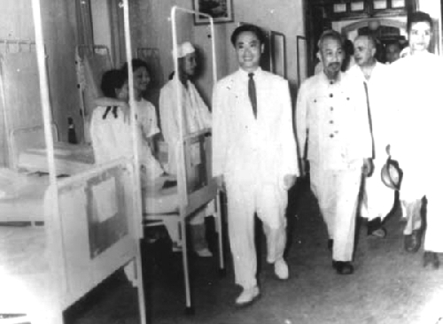 GS. Tôn Thất Tùng (người mặc complet trắng bên trái) hướng dẫn Chủ tịch Hồ Chí Minh thăm Bệnh viện Việt - Đức sau ngày Hà Nội giải phóng (10/10/1954).