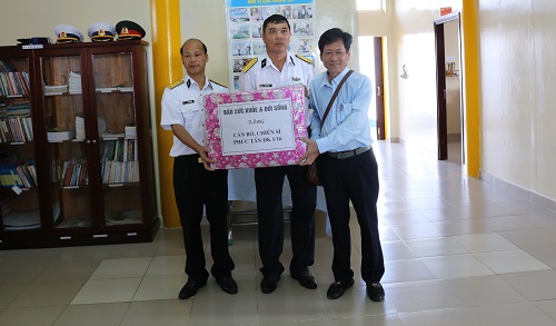TTND.BS. Trần Sĩ Tuấn - Tổng biên tập báo SK&ĐS (bên phải ảnh) trao quà tặng cho cán bộ chiến sĩ  Nhà giàn DK1/16 Phúc Tần.