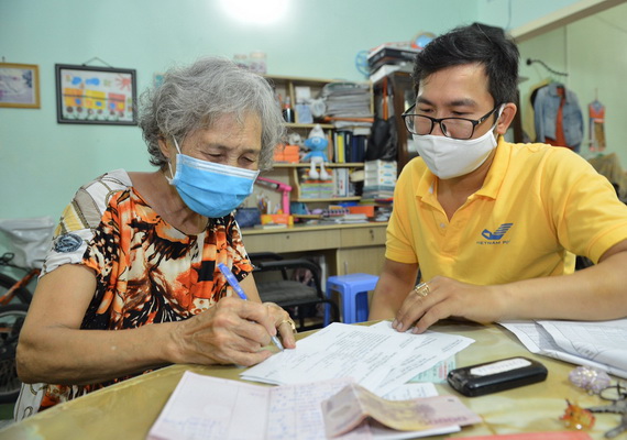 Người hưởng phấn khởi khi được nhận lương hưu, trợ cấp BHXH tại nhà ở phường Tân Định, quận 1, TP. HCM.