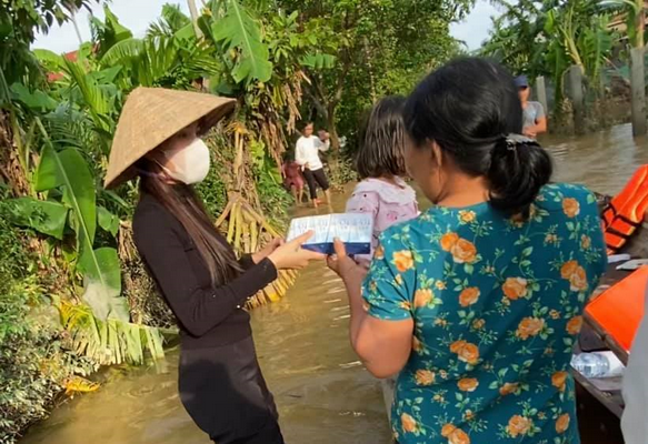 Ca sĩ Thủy Tiên (người đội nón) vừa đến vùng lũ trao nhu yếu phẩm cho người dân gặp khó khăn do lũ lụt.