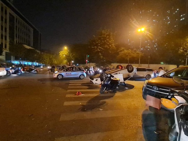 Ô tô phóng nhanh hất văng 2 người trên xe máy rồi lật ngửa ở Hà Nội - Ảnh 1.