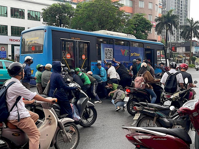 Cận cảnh người dân nâng xe buýt cứu tài xế mắc kẹt - Ảnh 2.