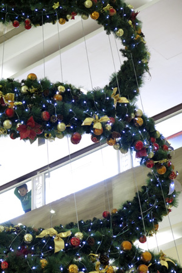 Một chú bé nhìn ngắm cây thông Noel có rất nhiều quả bóng màu sắc sặc sỡ.