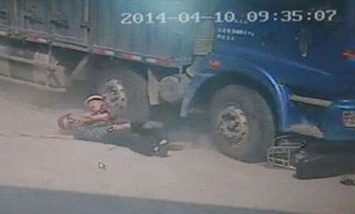 Yung Kuo, left, is pushed to safety by his father Hsiung as the lorry smashes into the scooter they were riding into the city of Quanzhou, China