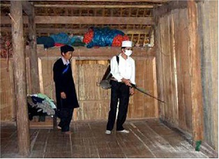 Nhân viên y tế phối hợp với gia đình trong việc phun hóa chất diệt muỗi.