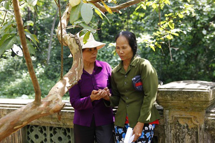 Người phụ nữ áo nâu (bên trái) đang tác nghiệp bói toán cho du khách tại khu Lăng mộ vua Lê Thái Tổ