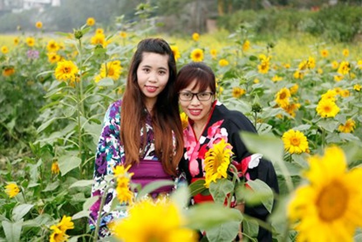 Hai cô gái trẻ khoe sắc giữa vườn hoa hướng dương