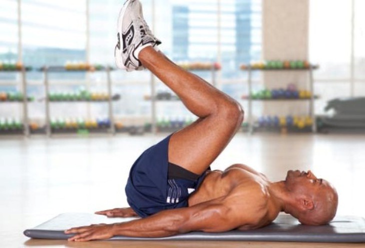 2. The reverse crunch (Gập bụng ngược):  Bước 1: Nằm ngửa trên mặt đất, chân duỗi thẳng, để hai tay song song với cơ thể, lòng bàn tay đặt cố định trên mặt đất.  Bước 2: Nâng chân lên cho tới khi đùi vuông góc với mặt đất và hai bàn chân sát vào nhau để song song với mặt đất. Bước 3: Trở lại vị trí ban đầu, nhưng không để chân chạm xuống đất. Điều này giúp duy trì sự căng cơ bụng trong suốt quá trình tập luyện. Lặp lại động tác này 12 lần. Ảnh: Webmd.