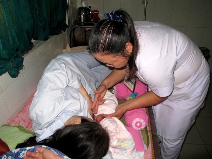 Điều dưỡng đang hướng dẫn cho bà mẹ cách cho trẻ bú.