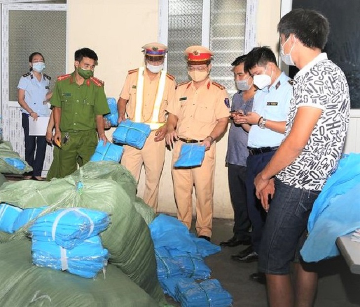 Lực lượng chức năng kiểm tra số quần áo bảo hộ y tế không rõ nguồn gốc xuất xứ. Ảnh: Công an tỉnh Hà Nam.
