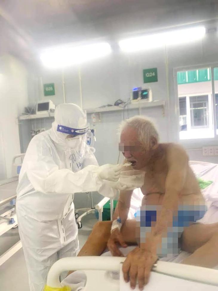 Điều dưỡng của Trung tâm hồi sức người bệnh COVID-19 Việt Đức đang bón từng thìa cháo và dỗ dành cụ T ăn. Ngoài việc chăm sóc vệ sinh, ăn uống cho bệnh nhân, các y bác sĩ còn động viên tinh thần người bệnh mỗi ngày để họ nhanh chóng hồi phục sức khỏe Điều dưỡng của Trung tâm hồi sức người bệnh COVID-19 Việt Đức đang bón từng thìa cháo và dỗ dành cụ T ăn. Ngoài việc chăm sóc vệ sinh, ăn uống cho bệnh nhân, các y bác sĩ còn động viên tinh thần người bệnh mỗi ngày để họ nhanh chóng hồi phục sức khỏe