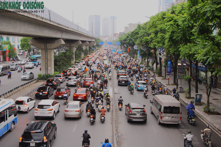 Hà Nội "hạ nhiệt", người dân ra đường mặc áo mưa thay vì áo chống nắng - Ảnh 1.