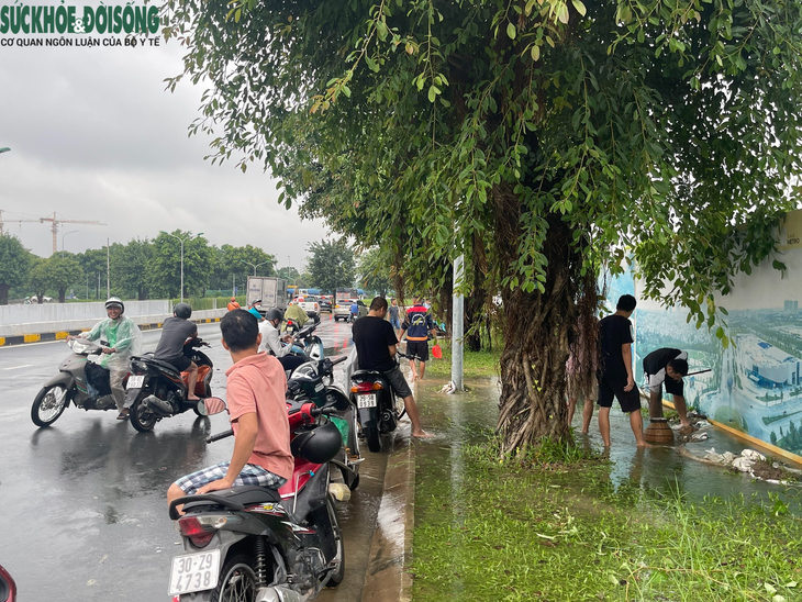 Người dân Hà Nội đua nhau bắt cá ở đường lớn sau trận mưa lớn - Ảnh 1.