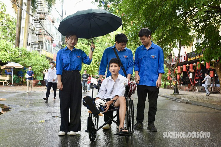 Hà Nội: Thí sinh bị gãy chân vừa mổ cấp cứu được sinh viên tình nguyện đưa vào phòng thi- Ảnh 1.