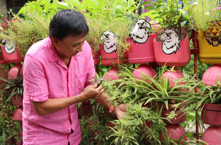Ông Chánh vừa làm chậu, trồng cây vừa chăm sóc, tưới nước cho cây dọc tuyến đường. Ảnh: Xuân Dự Ông Chánh vừa làm chậu, trồng cây vừa chăm sóc, tưới nước cho cây dọc tuyến đường. Ảnh: Xuân Dự