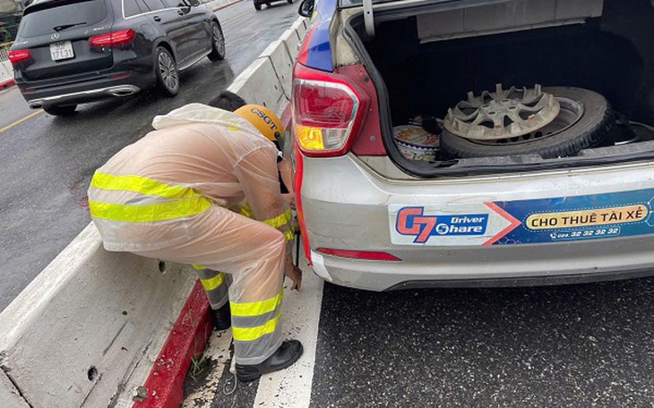 Hình ảnh đẹp về Đại úy CSGT hỗ trợ thay lốp cho xe taxi trong ngày mưa