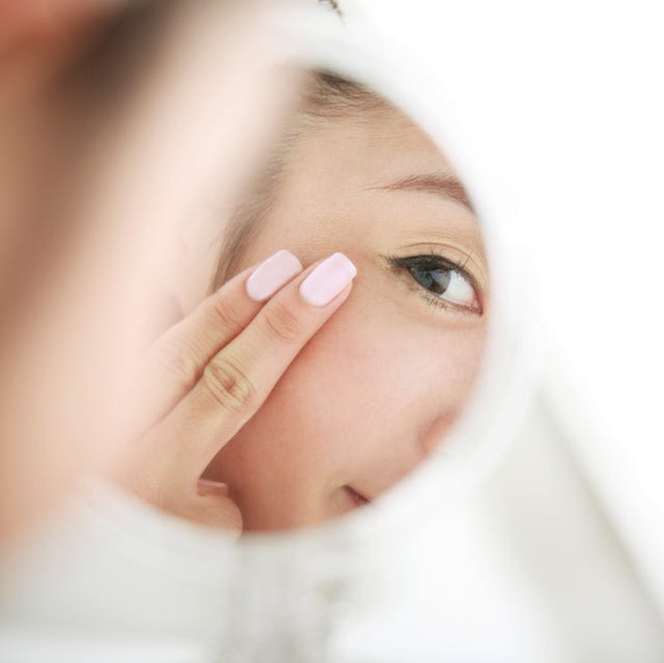 cách chăm sóc da mắt, phụ nữ trẻ nhìn mình trong gương chăm sóc da