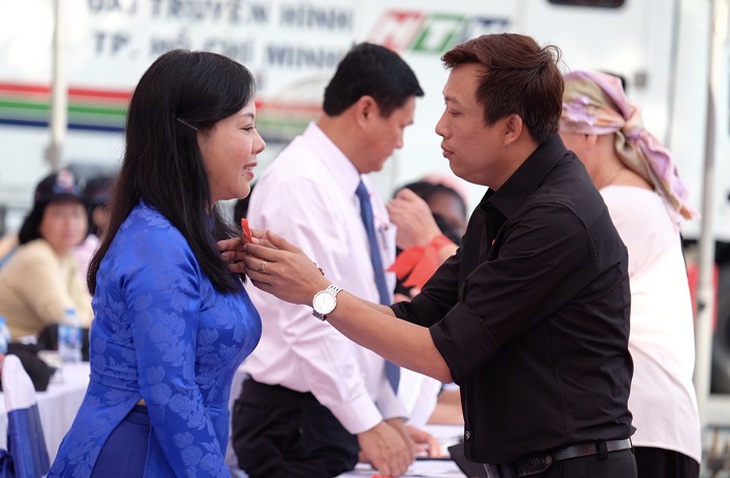 Đại diện Mạng lưới người sống với HIV tại TP.HCM cài chiếc nơ ruy băng đỏ biểu tượng phòng chống HIV cho Bộ trưởng Bộ Y tế Nguyễn Thị Kim Tiến
