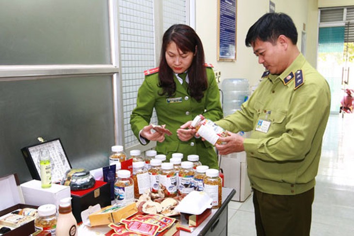 Lực lượng chức năng kiểm tra các sản phẩm thực phẩm chức năng vừa bị bắt giữ. Ảnh: TTXVN