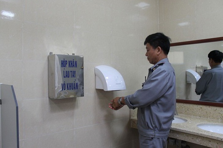 Nhà vệ sinh BV E có hộp để khăn lau tay vô khuẩn và máy sấy tay.