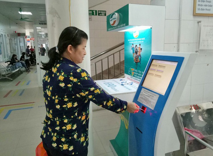 Người dân quẹt thẻ đăng ký phòng khám và lấy số phòng khám tại BV Bãi Cháy.