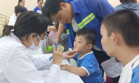 Ba người cùng cân một em nhỏ trong ngày khám sức khỏe đặc biệt